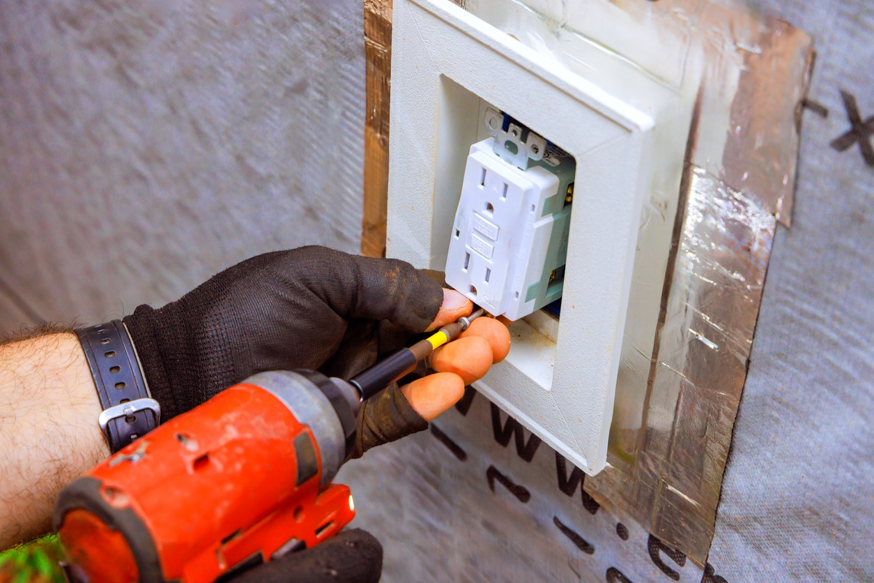Photo of someone installing a new GFCI receptacle in a wall box.