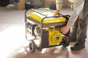 A homeowner lugs a portable generator out of the garage. 
