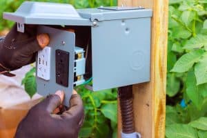 A licensed electrician installs a lifted outdoor GFCI outlet in a Missouri backyard.
