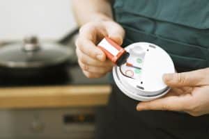 A homeowner changes out the battery in his smoke detector. 