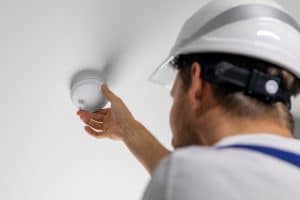 A licensed electrician inspects and tests residential smoke alarms. 